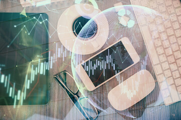 Multi exposure of forex graph hologram over desktop with phone. Top view. Mobile trade platform concept.