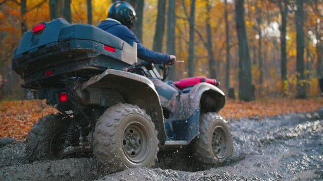 Outdoor activity -people riding ATVs in the forest on a muddy track