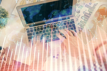 Double exposure of man's hands typing over laptop keyboard and forex chart hologram drawing. Top view. Financial markets concept.