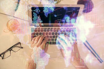 Double exposure of man's hands typing over laptop keyboard and forex chart hologram drawing. Top view. Financial markets concept.