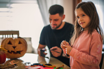 Father and children make decorations for Halloween at home.