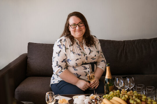 Portrait of a large woman with a glass of wine sitting on the sofa