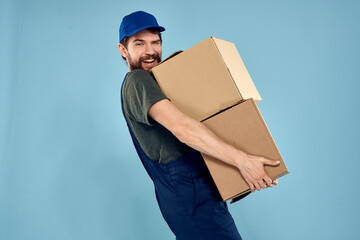 Man in working uniform with boxes in hands delivery service blue background