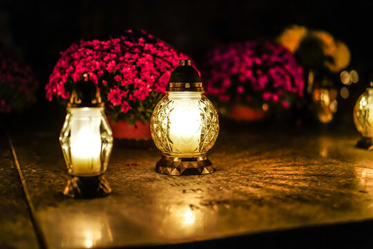Lit grave candles standing on a grave. Grave lanterns in the cemetery on the All Saints' Day.