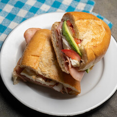 Mexican ham sandwich with avocado and cheese also called torta on dark background