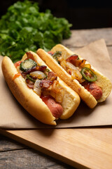 Hot dog with jalapeno pepper, bacon and caramelized onion on wooden background