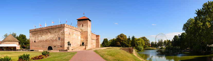 Fototapeta na wymiar The only remaining brick-built medieval fortress.In front of the castle you can see a boating lake and in the background a Ferris wheel. Big size panorama view, Hungary, Gyula
