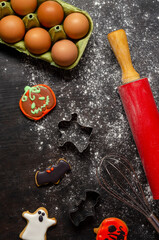 making cookies for halloween. Rolling pin, whisk, ready-made cookies on a dark background.