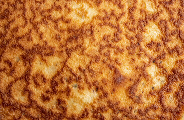 Omelette, frittata texture or Spanish tortilla, top view.  Close up of fried yellow egg with golden brown caramelization. Abstract rough grunge texture pattern with craters and valleys.