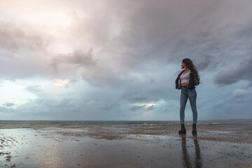 Young woman attending how the waves hit the rocks.