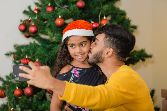 Summer Christmas Dinner In Brazil. Real Brazilian Family Having Fun At The Latin American Christmas Party. Father Making A Selfie Giving A Kiss To His Daughter With Curly Hair