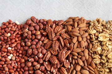 Raw peeled peanuts, hazelnuts, pecans, almonds and walnuts on a linen cloth. Closeup. Macro