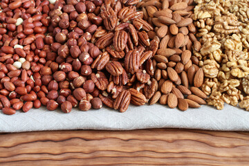 Raw peeled peanuts, hazelnuts, pecans, almonds and walnuts on a linen cloth. Closeup. Macro