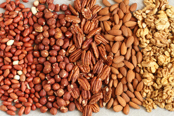 Raw peeled peanuts, hazelnuts, pecans, almonds and walnuts on a linen cloth. Closeup. Macro