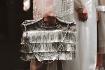 Woman's hand holding a stylish fashionable silver bag made of thread and chain. Fashion Week shot