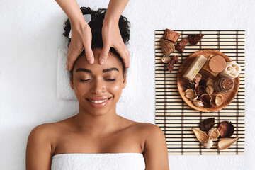 Smiling african woman enjoying facial massage at spa