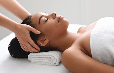 Obraz na płótnie Canvas Female masseuse massaging relaxed black lady head
