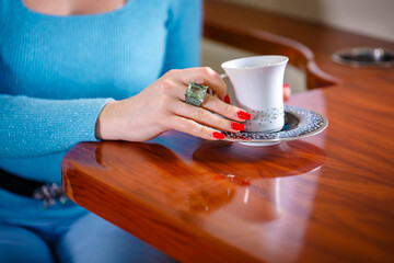 Fototapeta na wymiar female hand with a ring holding a cup of tea in business class the flight 