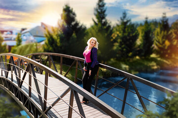 young positive, smiling, legant woman walks on a wooden footbridge on a sunny autumn day