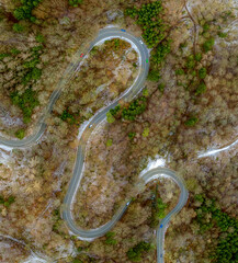 Winding road in the transition from autumn to winter, snow at a germany roa, filmed straight from above.