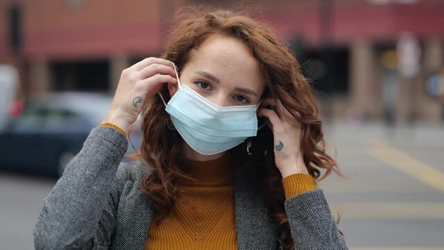 Red haired woman putting on facemark