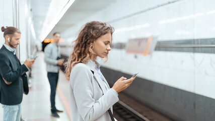 passengers wait for the train standing on the subway platform.