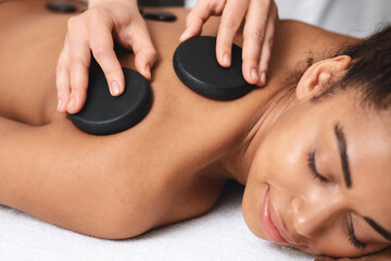 Closeup of black lady having healing hot stone massage
