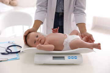 Obraz na płótnie Canvas Doctor weighting cute baby in clinic, closeup. Health care