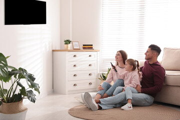 Fototapeta premium Happy family watching TV on floor at home