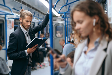 young man reading a book on a subway train.