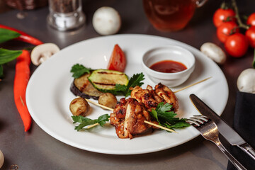 Barbecued marinated turkey or chicken meat shish kebab skewers with ketchup sauce and grilled vegetables on rustic wooden table background
