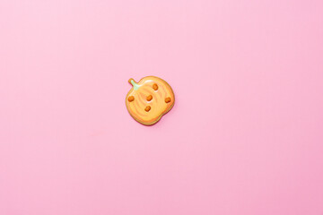 Sweet homemade pumpkin cookie with icing isolated on pink background minimal flat lay composition.