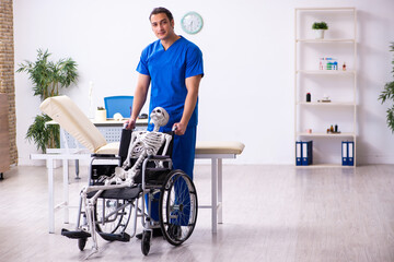 Young male doctor and skeleton in wheel-chair