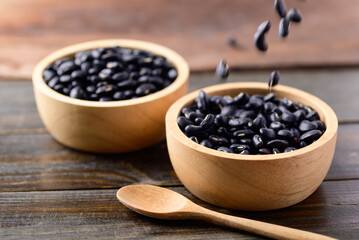 Black kidney beans in a bowl and spoon on wooden background