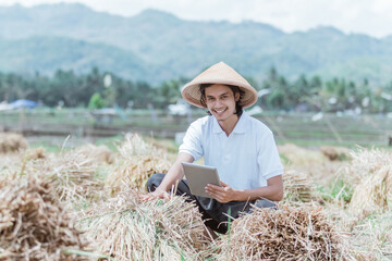 Naklejka na ściany i meble the farmer smiled while showing the rice crop yields when using a tablet pc in the fields