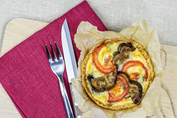 Top view to french mini tart quiche with vegetables like mushrooms, eggplants, tomatoes on the fabric background. 