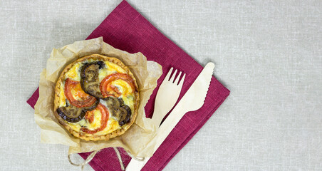 Top view to french mini tart quiche with vegetables like mushrooms, eggplants, tomatoes on the fabric background.  Copy space.