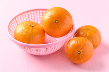 Fresh Honey Murcott orange fruit in a basket on pink background