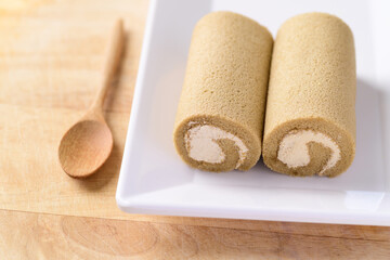 Coffee roll cake on white dish with spoon ready to eating
