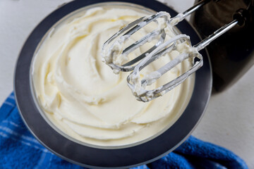 Fototapeta na wymiar White butter cream in bowl with mixer whisk.