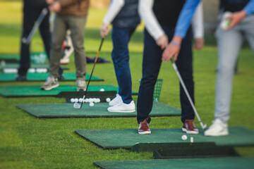 Group of golfers practicing and training golf swing on driving range practice, men playing on golf...