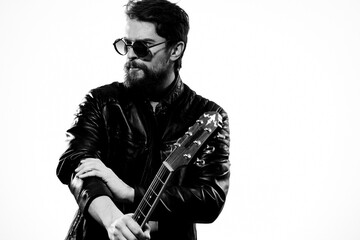 A man holds a guitar in his hands music emotions black leather jacket dark glasses studio light...