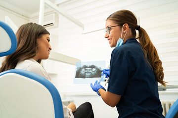 Obraz premium Dentist and patient looking her teeth xray and smiling 