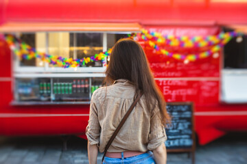 Girl ordering street food in colourful food truck van on food festival, summer sunny day