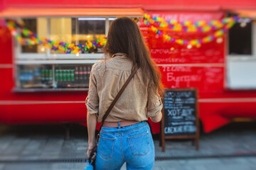 Girl ordering street food in colourful food truck van on food festival, summer sunny day