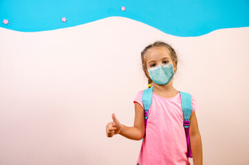 Child kindergarten age with protective face mask showing thumbs up. Copy space