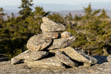 Long shadows form among the rocks of a cairn as the sun sets along a mountaintop hiking trail