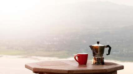 cup of coffee with moka pot on mountain view background