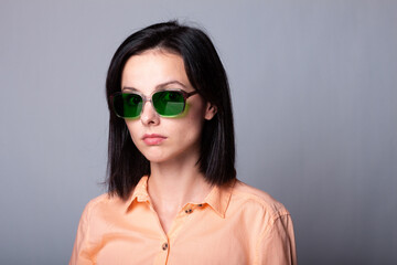 woman in glasses with green lenses, gray background