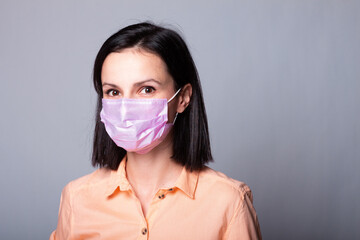 woman in shirt and medical mask, gray background